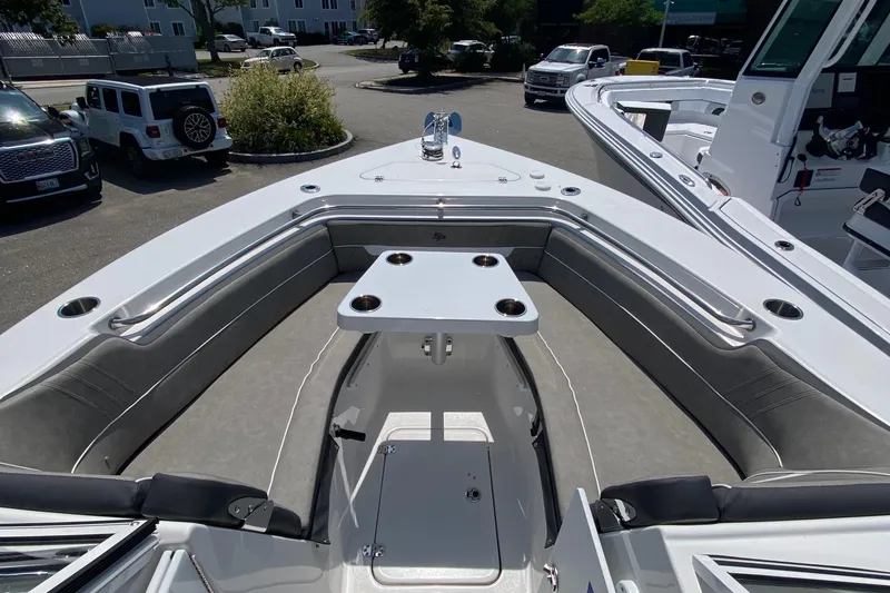 Slide: The Image of 2024 Sea Pro 240 Dual Console boat interior with seating and table, parked outdoors. - 15
