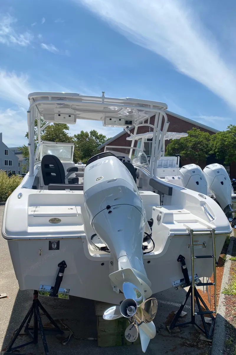 Slide: The Image of 2024 Sea Pro 240 Dual Console boat with outboard motor, parked outdoors under a blue sky. - 3