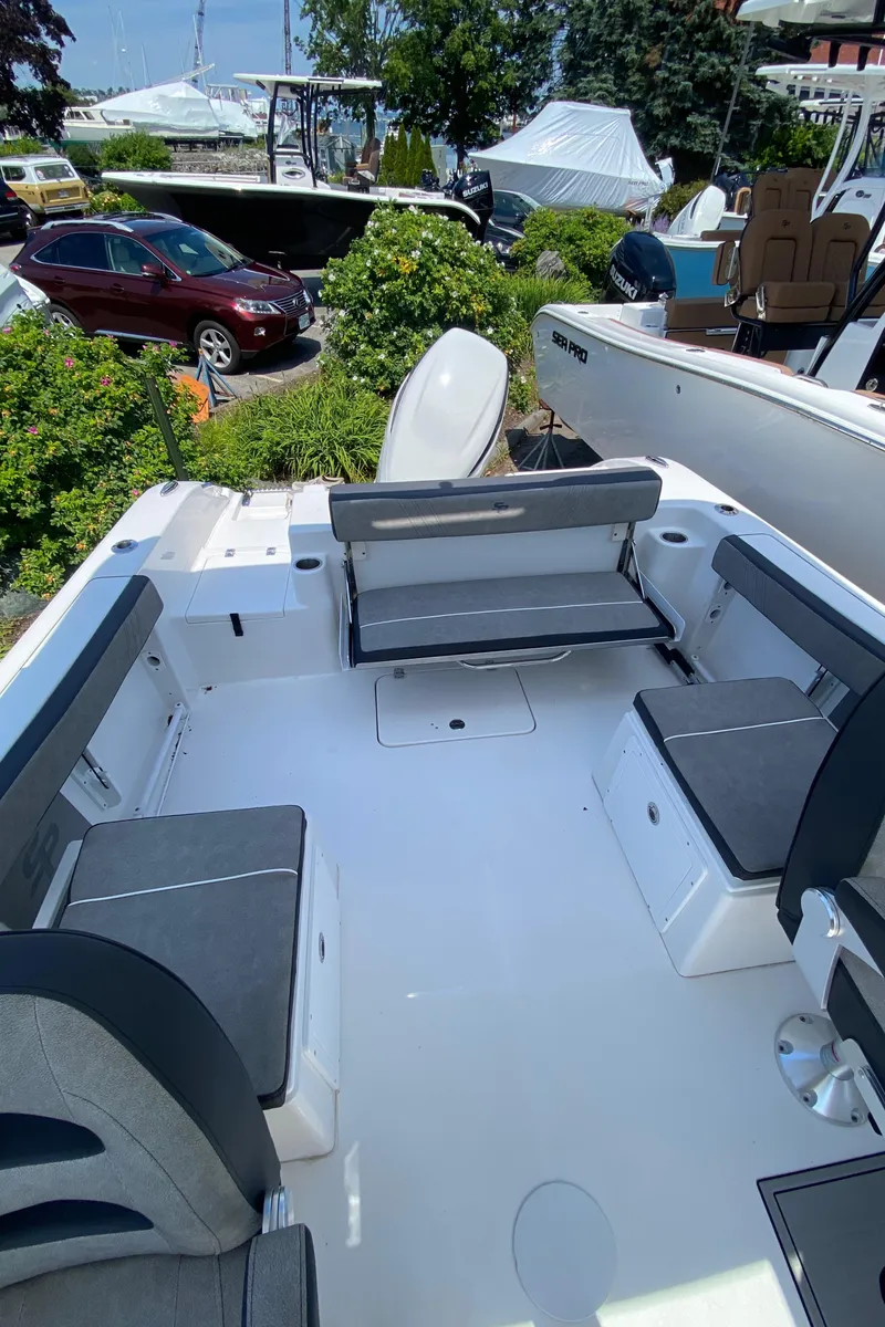 Slide: The Image of 2024 Sea Pro 240 Dual Console boat interior with seating and storage, docked outdoors. - 7