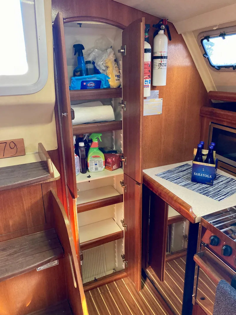 Slide: The Image of Interior of 2005 Hunter 41 AC sailboat with open cabinet and kitchen essentials. - 29