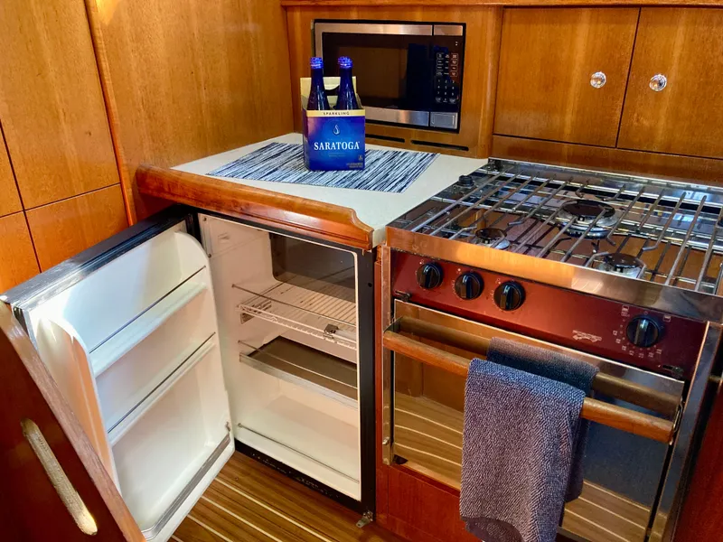 Slide: The Image of 2005 Hunter 41 AC yacht kitchen with open fridge, stove, and microwave. - 33