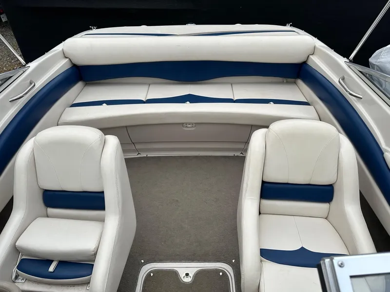 Slide: The Image of 2002 Larson SEI 210 boat interior with white and blue seating, spacious layout. - 4