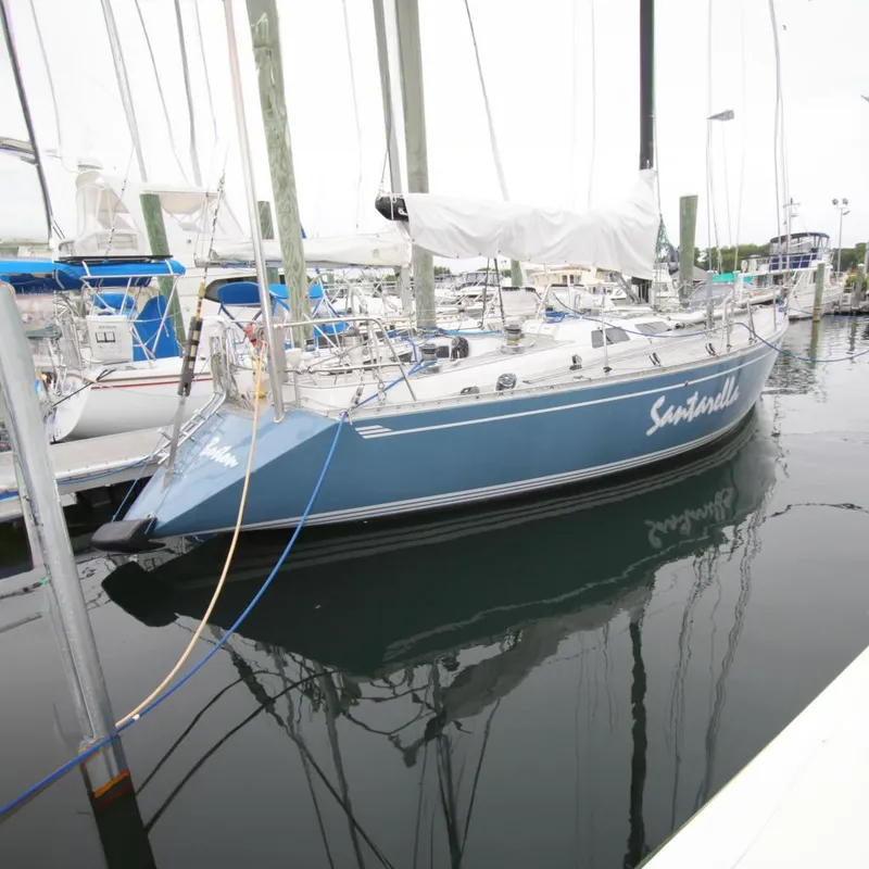 Slide: The Image of 1983 Baltic 38DP sailboat docked in marina, blue hull, white deck, named "Santarella". - 0