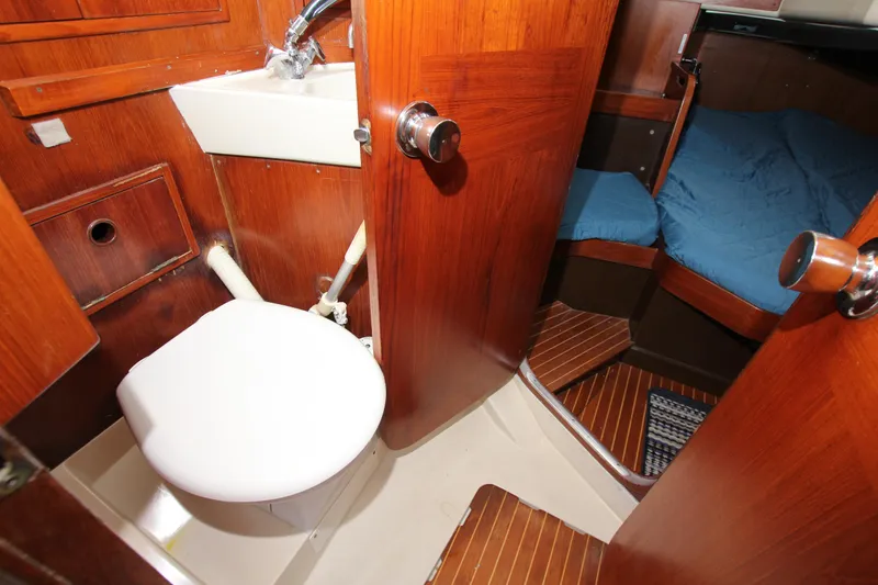 Slide: The Image of 1983 Baltic 38DP yacht interior with wooden finish, featuring a compact bathroom and cozy sleeping area. - 28
