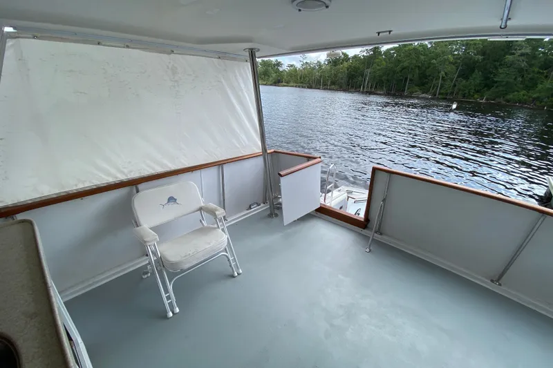 Slide: The Image of Deck of 1990 Californian 52 yacht with chair, overlooking serene water and lush greenery. - 28