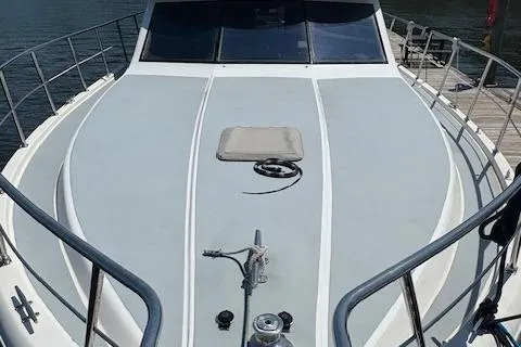 Slide: The Image of 1990 Carver Californian 52 yacht deck with railing and hatch, docked by the water. - 2