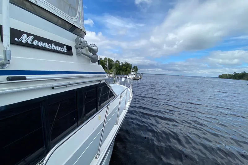 Slide: The Image of Californian 52 yacht "Moonstruck" docked by a serene lake, under a partly cloudy sky. - 19