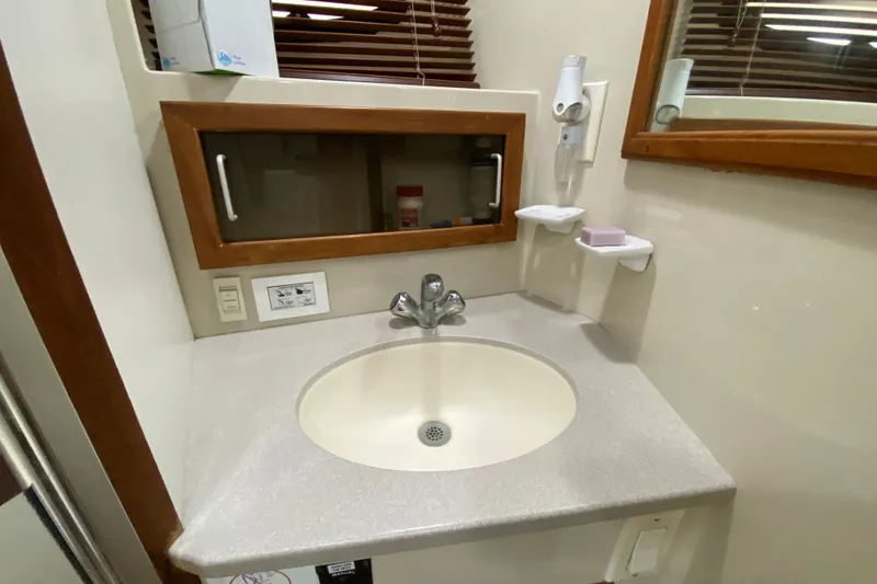 Slide: The Image of Bathroom sink area in a 1990 Californian 52 yacht, featuring a mirror and faucet. - 77