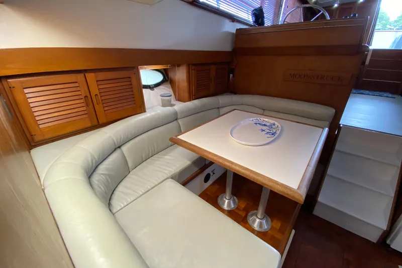 Slide: The Image of Cozy dining area in a 1990 Californian 52 yacht with wooden accents and plush seating. - 72