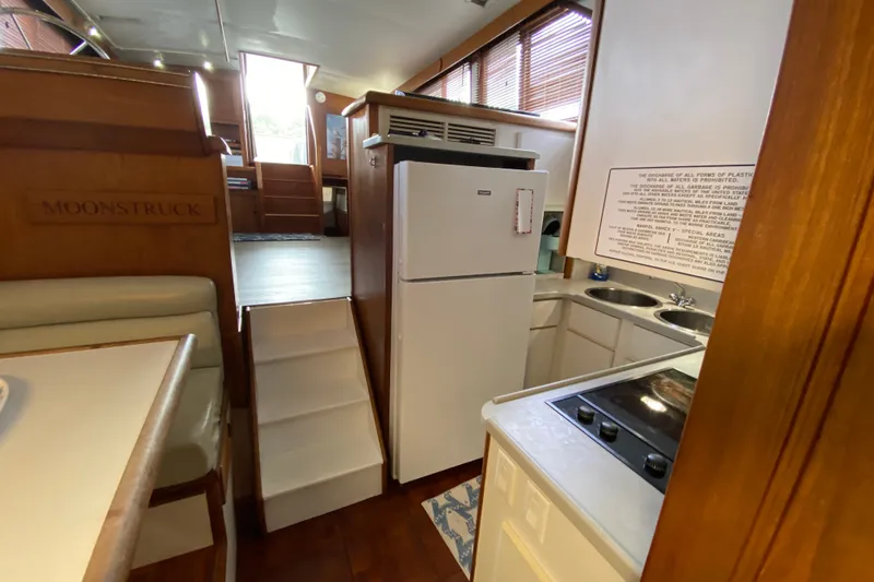 Slide: The Image of Interior of a 1990 Californian 52 yacht featuring a compact kitchen and dining area. - 67