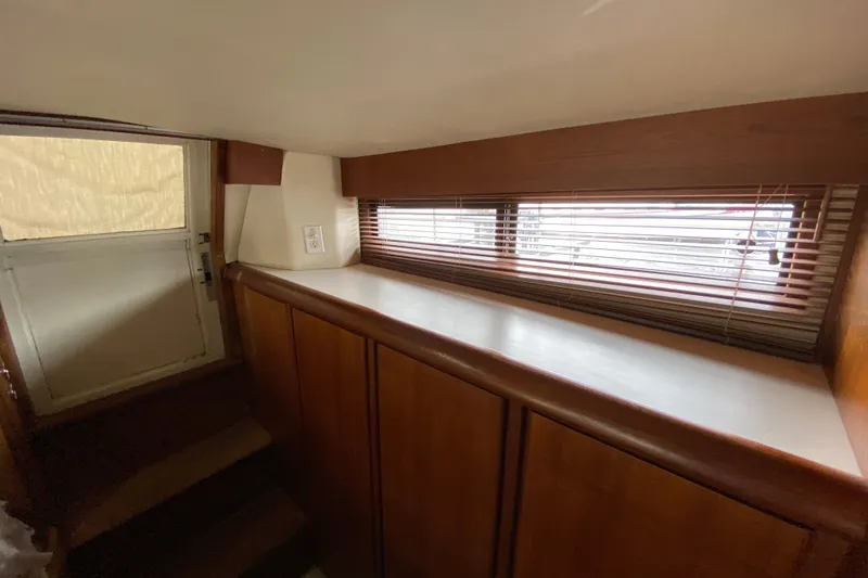 Slide: The Image of Interior of a 1990 Californian 52 yacht with wooden cabinets and window blinds. - 59
