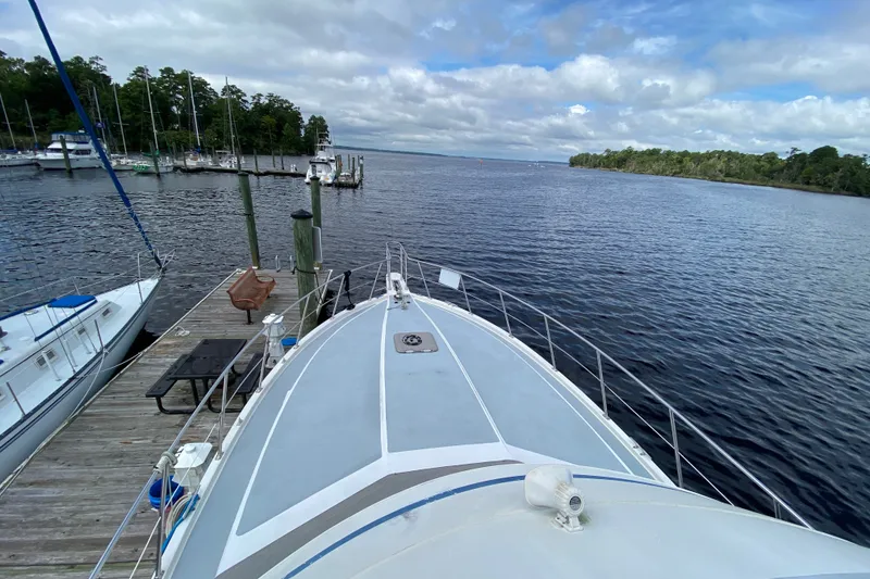Slide: The Image of Bow view of a 1990 Californian 52 yacht docked at a serene marina. - 20