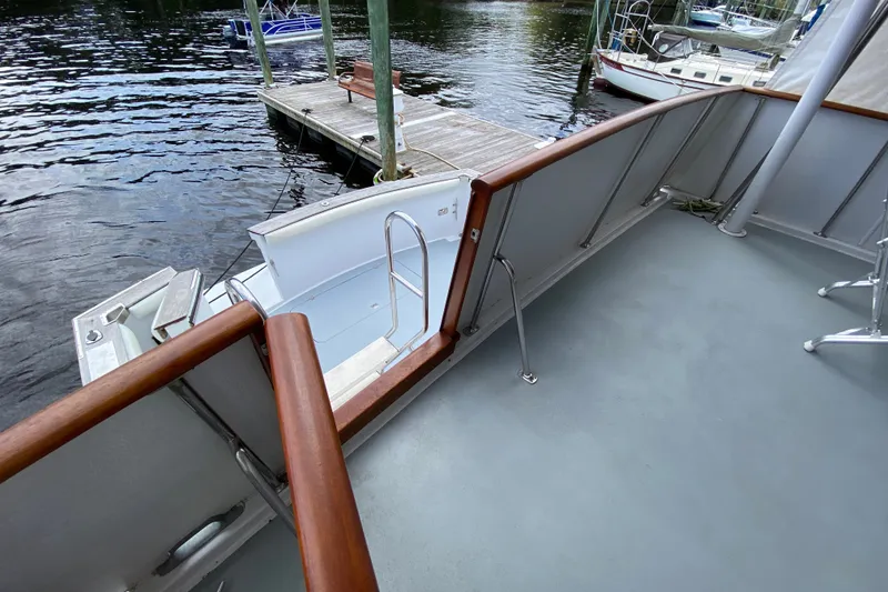 Slide: The Image of 1990 Californian 52 yacht deck with wooden railings, docked by a serene waterfront. - 13