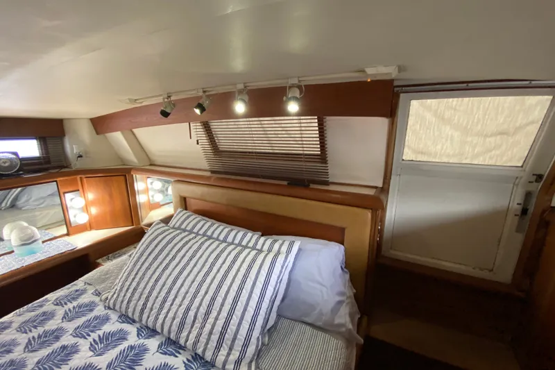 Slide: The Image of Interior of a 1990 Californian 52 yacht bedroom with striped bedding and wooden accents. - 57