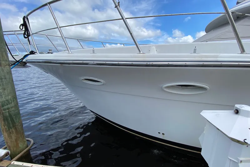 Slide: The Image of 1990 Californian 52 yacht docked, showcasing sleek white hull and railing under blue sky. - 3