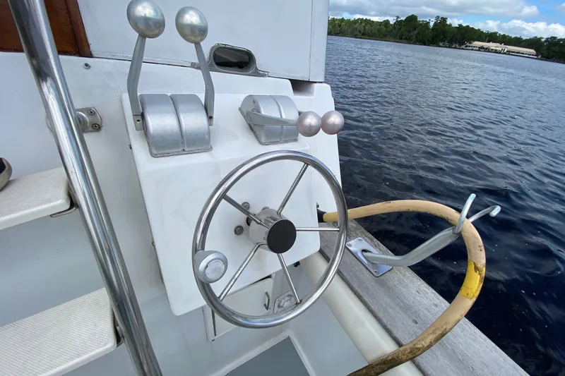 Slide: The Image of Steering wheel and controls of a 1990 Californian 52 boat on a lake. - 11