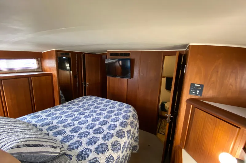 Slide: The Image of Cozy bedroom interior of 1990 Californian 52 yacht with wood paneling and patterned bedding. - 54
