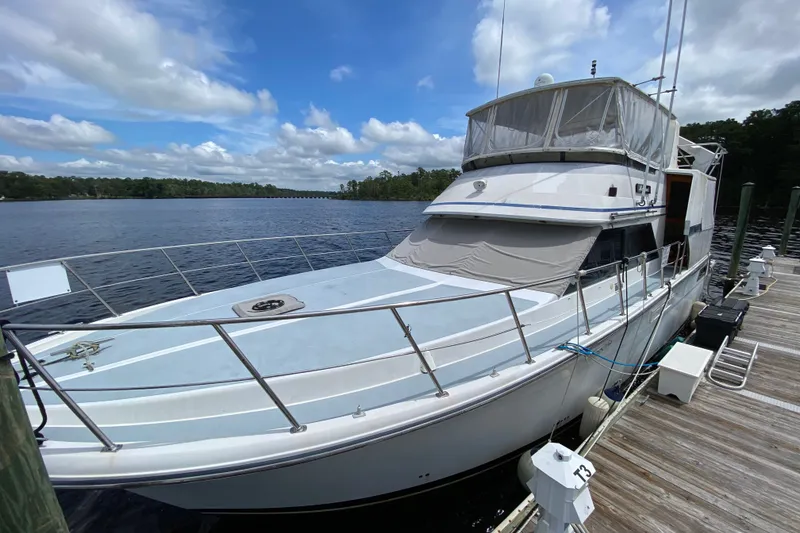 The Image of 1990 Californian 52 yacht docked on a serene lake under a partly cloudy sky. - 0