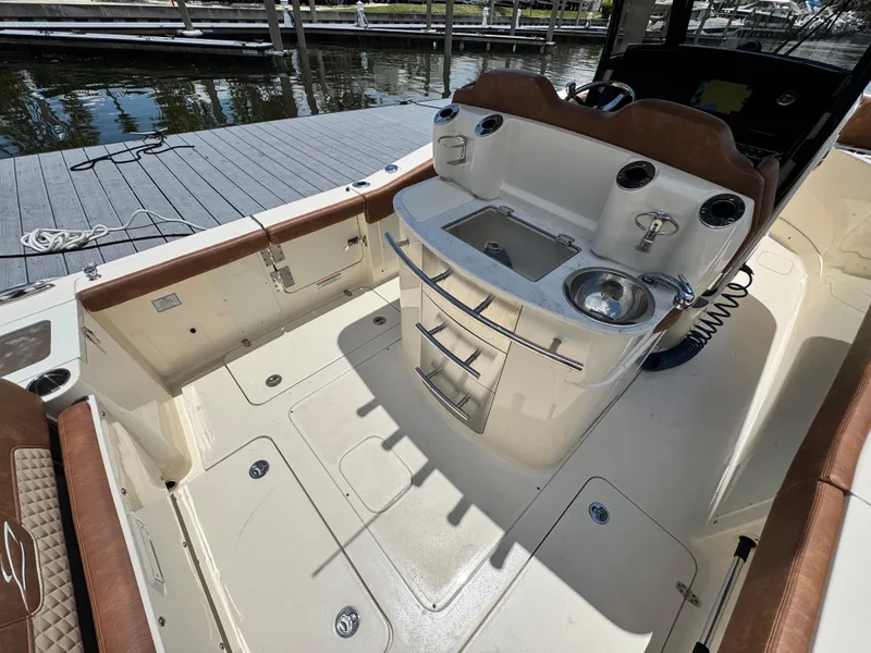 Slide: The Image of 2024 Scout 277 LXF boat interior with seating and sink at dock. - 13