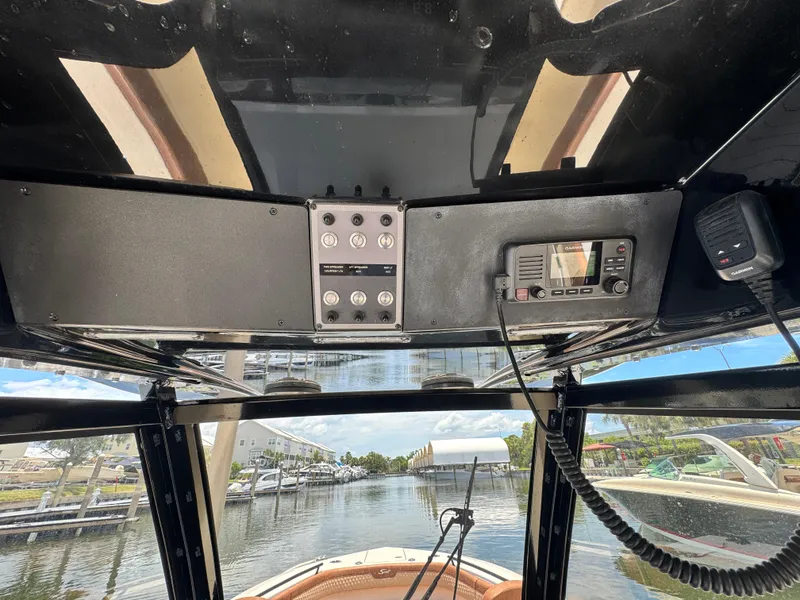 Slide: The Image of 2024 Scout 277 LXF boat dashboard with navigation controls and scenic marina view. - 21