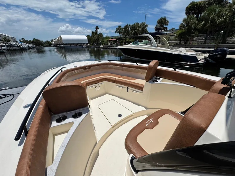 Slide: The Image of 2024 Scout 277 LXF boat interior with luxurious seating and cup holders, docked by a scenic waterfront. - 23