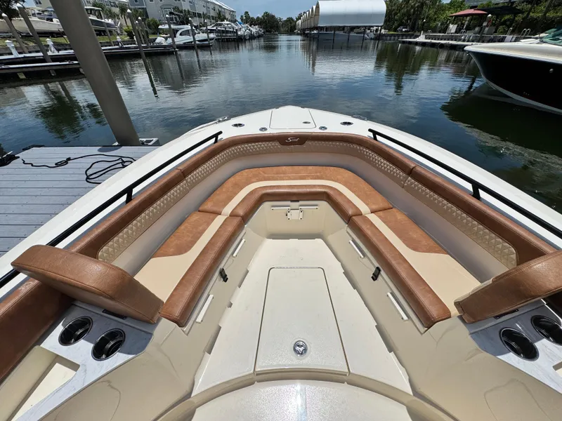 Slide: The Image of 2024 Scout 277 LXF boat with luxurious tan seating in a marina setting. - 24
