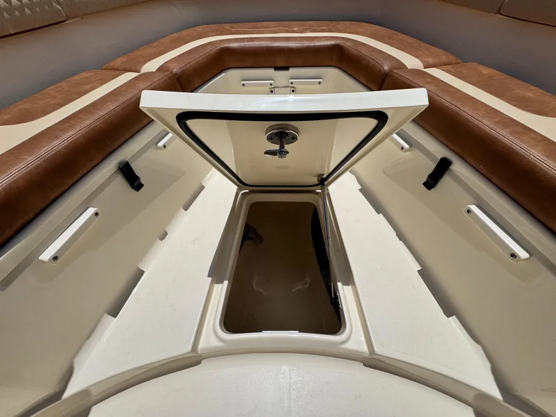 Slide: The Image of 2024 Scout 277 LXF boat storage compartment with open hatch and cushioned seating. - 26