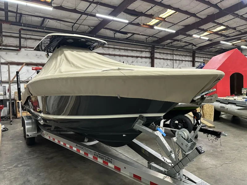 Slide: The Image of 2024 Scout 277 LXF boat covered on trailer in warehouse setting. - 4