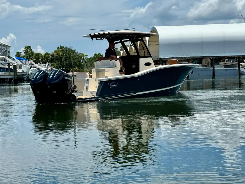Slide: The Image of 2024 Scout 277 LXF boat on calm water with dual Mercury engines. - 5