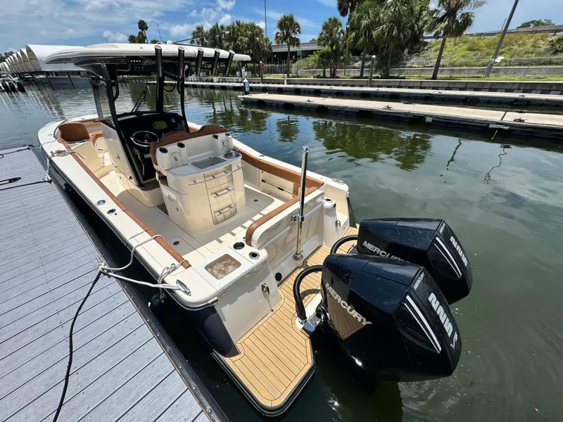 Slide: The Image of 2024 Scout 277 LXF boat docked with dual Mercury engines, sleek design, and spacious deck. - 9