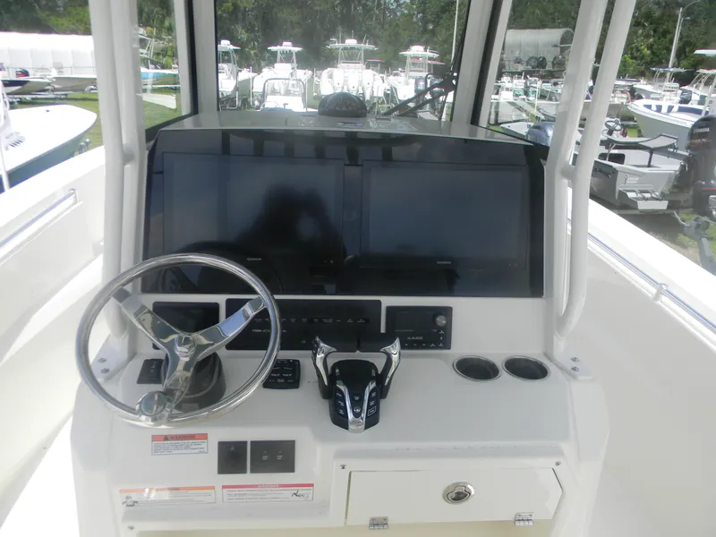 Slide: The Image of 2025 Cobia 285 Center Console helm with dual screens and steering wheel. - 18
