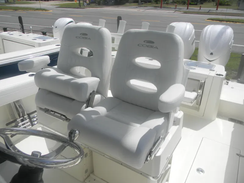 Slide: The Image of 2025 Cobia 285 Center Console boat with white cushioned seats and steering wheel. - 25