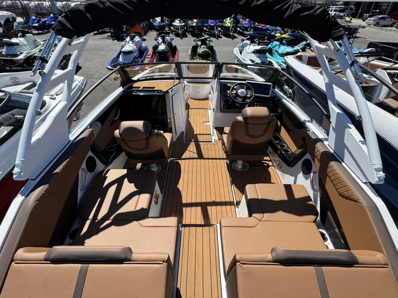 Slide: The Image of 2025 Yamaha Boats 222SD interior with brown seating and modern dashboard, docked among other boats. - 4
