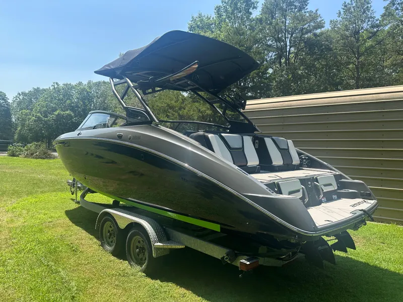 The Image of 2021 Yamaha Boats 255XD on trailer, parked on grass, with trees in background. - 1