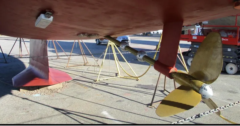Slide: The Image of 2003 CNB 64 sailboat on stands, black hull, red bottom, in shipyard. - 32