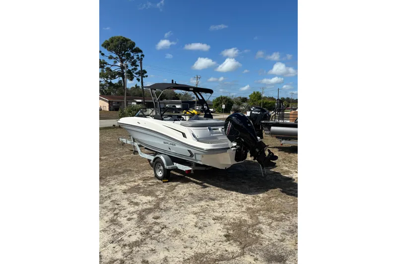 Slide: The Image of 2025 Bayliner VR5 Bowrider OB on trailer, parked outdoors under clear blue sky. - 23