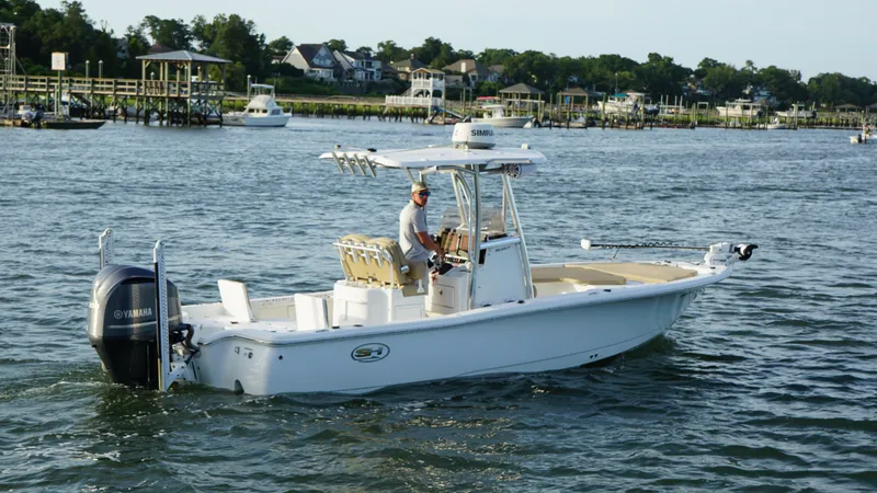 Slide: The Image of 2017 Sea Hunt BX 25 BR boat cruising on a scenic waterway with docks and houses. - 5