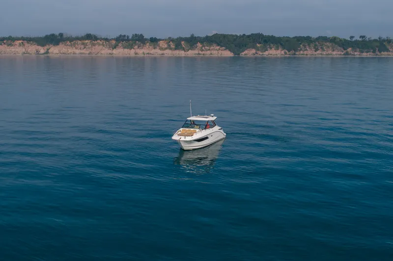 Slide: The Image of 2019 Sea Ray Sundancer 320 yacht on calm blue water with scenic coastline backdrop. - 20