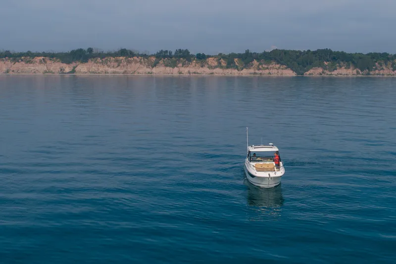 Slide: The Image of 2019 Sea Ray Sundancer 320 cruising on calm waters near a scenic coastline. - 21