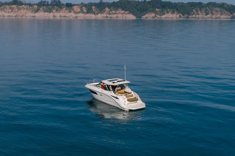 Slide: The Image of 2019 Sea Ray Sundancer 320 cruising on calm blue waters near a scenic coastline. - 22
