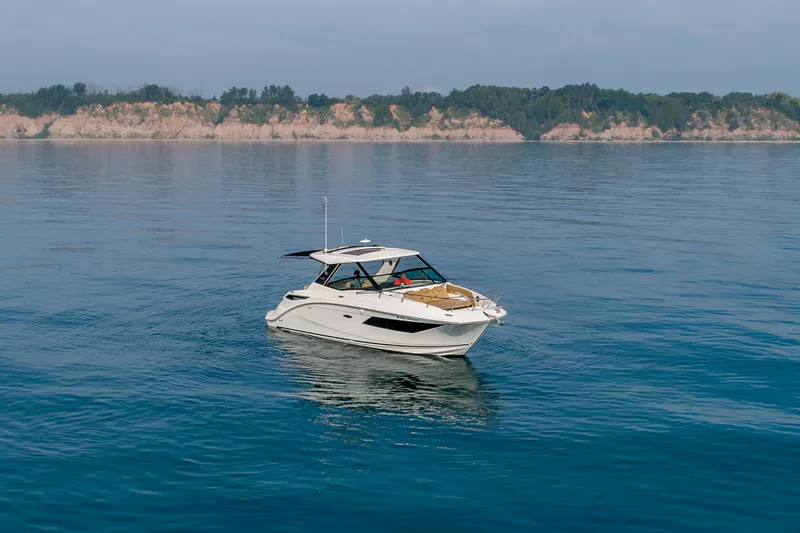 Slide: The Image of 2019 Sea Ray Sundancer 320 yacht cruising on calm waters near a scenic coastline. - 26