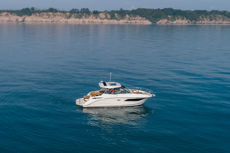 Slide: The Image of 2019 Sea Ray Sundancer 320 cruising on calm blue waters near a scenic coastline. - 28