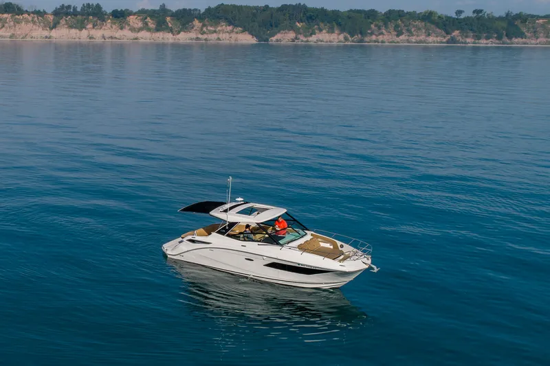 Slide: The Image of 2019 Sea Ray Sundancer 320 cruising on calm blue waters near a scenic coastline. - 29