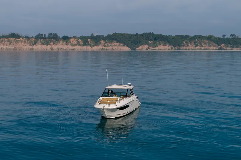 Slide: The Image of 2019 Sea Ray Sundancer 320 cruising on calm waters near a scenic coastline. - 30