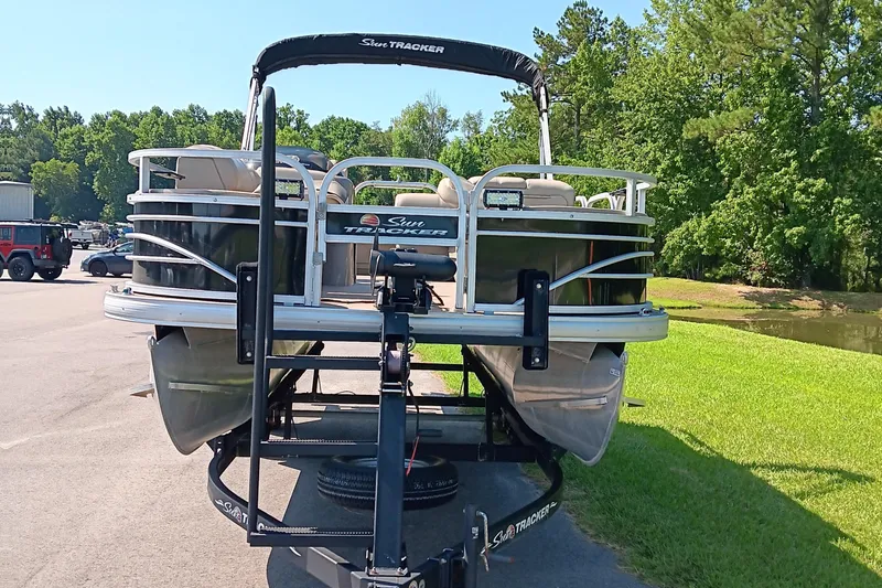 Slide: The Image of 2021 Sun Tracker Fishin' Barge 20 DLX pontoon boat on trailer, parked outdoors. - 4