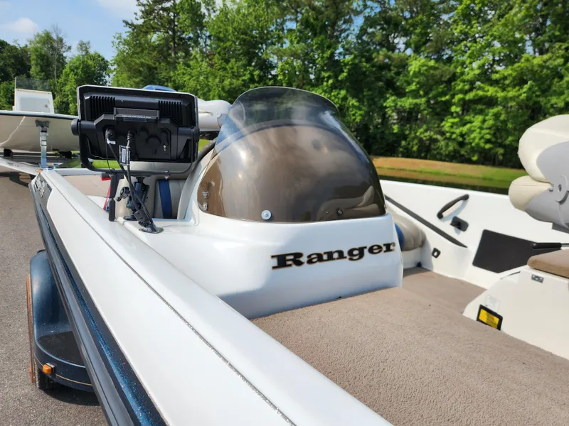 Slide: The Image of 2003 Ranger 195SVS boat with console and electronics, parked on a trailer, surrounded by greenery. - 11