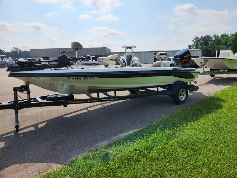 Slide: The Image of 2003 Ranger 195SVS boat on trailer, parked outdoors near grass and industrial buildings. - 6