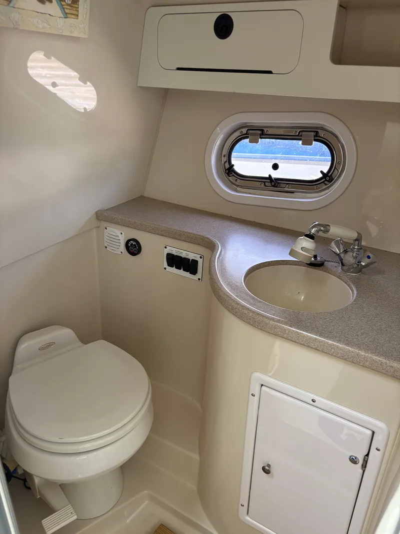 Slide: The Image of 2005 Four Winns 328 Vista Cruiser bathroom with sink, toilet, and porthole window. - 11