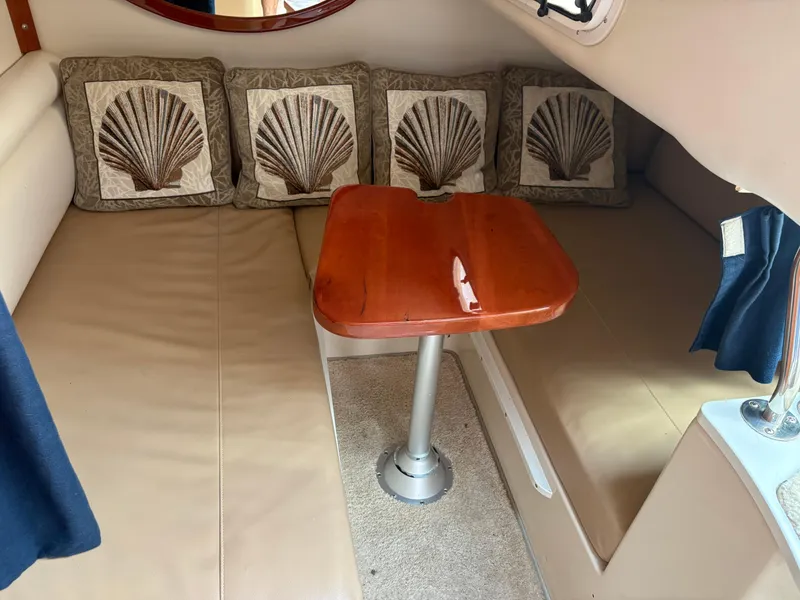 Slide: The Image of 2005 Four Winns 328 Vista Cruiser cabin with shell-themed cushions and wooden table. - 12