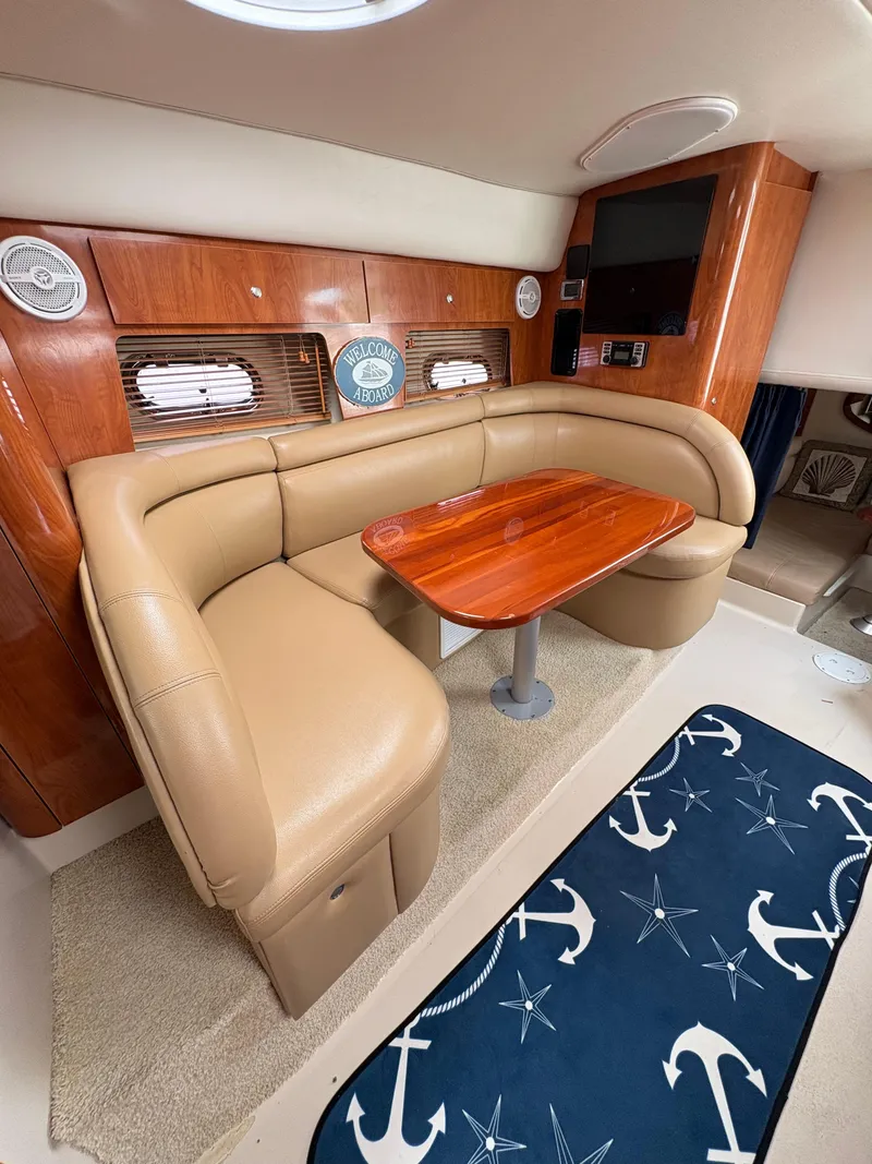 Slide: The Image of 2005 Four Winns 328 Vista Cruiser interior with leather seating, wooden table, and nautical decor. - 7